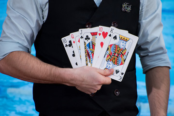 Magic, performance, circus, gambling, casino, poker, show concept - close up of magician hand holding playing cards