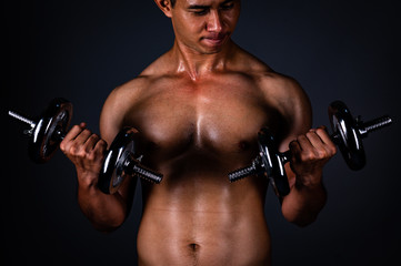 Naklejka na ściany i meble The strong Asian man lifted his dumbbell regularly to keep his muscles strong and beautiful