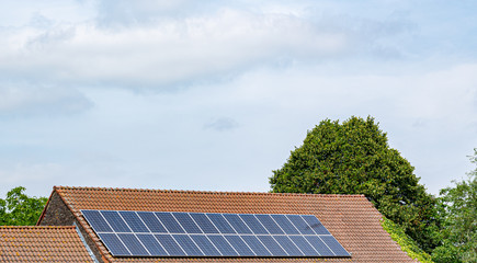 Energy, technology, electricity and ecological concept: solar panels on a house roof as a source of clean renewable energy.