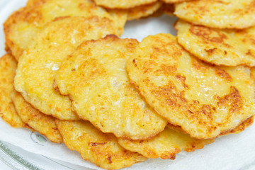 Homemade fried potato pancakes on a transparent plate.