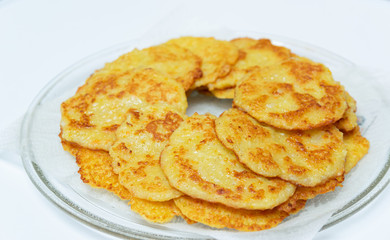 Homemade fried potato pancakes on a transparent plate.