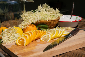 On a cutting board lies a kitchen knife and a sliced organic lemon and organic orange, in the...