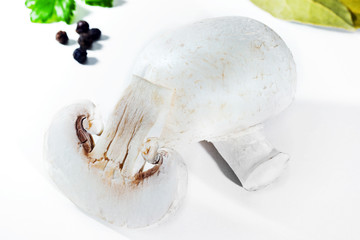 Two white mushroom mushrooms, one cut in two, on a white background, edible fresh mushrooms.