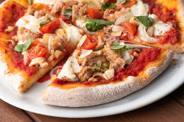 Fette di deliziosa pizza con tonno, cipolla, mozzarella e pomodorini 