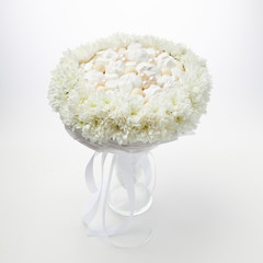 White bouquet of marshmallows and chocolates framed by white flowers stands in a vase on a white...