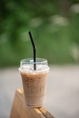 Iced coffee in a clear glass that can see the ice inside the glass and is placed in the coffee shop Green leaf background view