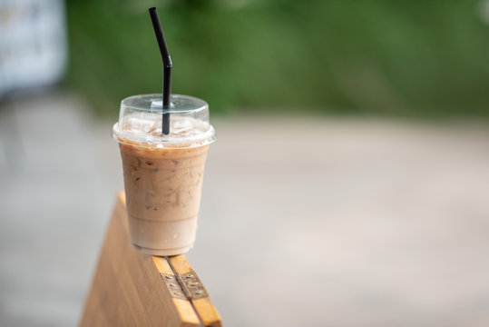 Iced Coffee In A Clear Glass That Can See The Ice Inside The Glass And Is Placed In The Coffee Shop Green Leaf Background View