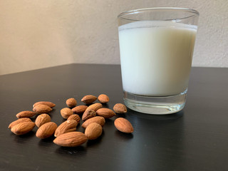 Kefir in a glass glass on a black wooden table with almonds on the side. Snack. Good nutrition