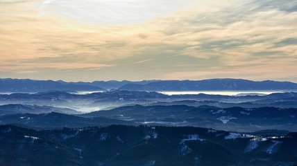 Obraz na płótnie Canvas Panoramic view of Mala Fatra mountain ridge from lookout at Lysa hora mountain at perfect visibility. The Main ridge is under snow. Misty morning in mountain valleys.
