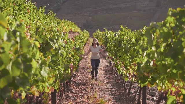 Free girl runs along the grass between vineyards. Happy day. To enjoy life