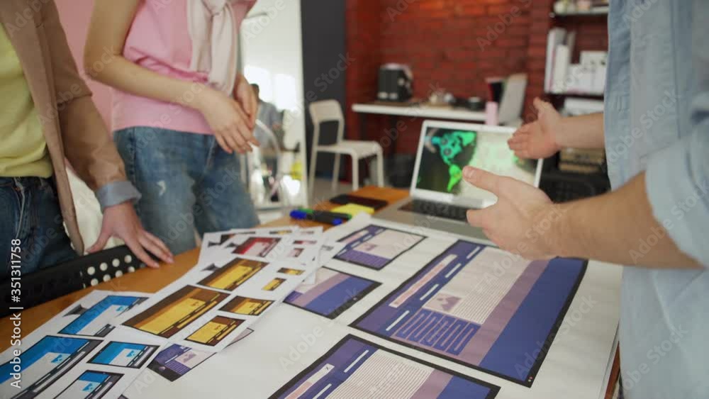 Wall mural hands of unrecognizable business team of three discussing printouts with website interface templates