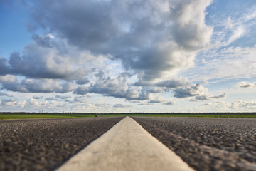Empty asphalt road on a background of beautiful cloudy sky, close-up