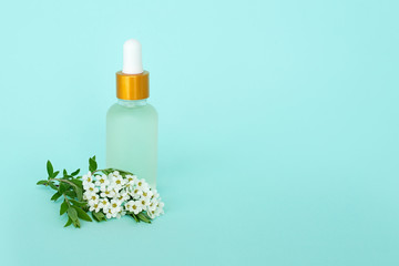 Glass cosmetik bottle with oil. container for a product for women with small white flowers on a turquoise background. Cosmetic jar. Place for text