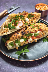 Healthy vegetarian tortilla or pita bread with chickpeas, vegetables and herbs served with homemade hummus in vintage dishes. Healthy eating concept. Dark background. Close-up. Copy space
