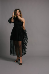 Elegant Young Woman Holding a White Flower in a Black Dress on a Grey Background