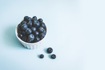 Fresh raw organic blueberry in a mug on blue surface, top view, flat lay