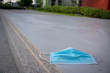 Blue disposable medical mask is on the road surface, on street. to prevent the Virus Covid-19. Concept viruses spread throughout the world. Do not throw away your used face mask. copy space.