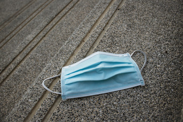 Blue disposable medical mask is on the road surface, on street. to prevent the Virus Covid-19. Concept viruses spread throughout the world. Do not throw away your used face mask. copy space.