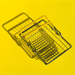 Metal mesh shopping basket in a supermarket. The view from the top. Yellow background.