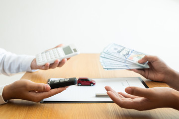 Customer is paying the rental fee to car rental representative after signed a car rental agreement...