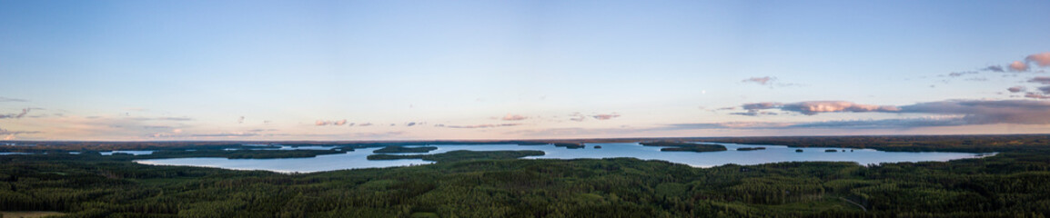 Panoramic lake side view of a lake at sunset in North Karelia, Finland. Thick forest surrounding the lakes.