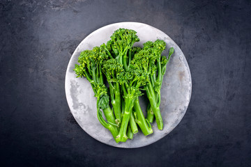 Frische Rapini Broccoli Rabe als Draufsicht auf einem grauen Teller mit Textfreiraum