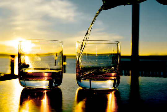 Whiskey Is Being Poured In Glass On Table