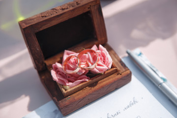 Two gold wedding rings in a beautiful wooden casket with green moss. Wedding accessories. Bride morning