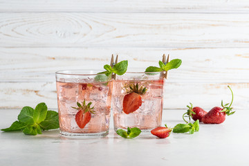 Fresh iced strawberry lemonade with mint on white wooden background. Refreshing summer drink on the table.