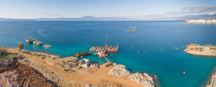 Panoramic aerial view of machinery on concrete platforms at the construction of future LNG terminal on the shore of the bay in Omisalj, Croatia