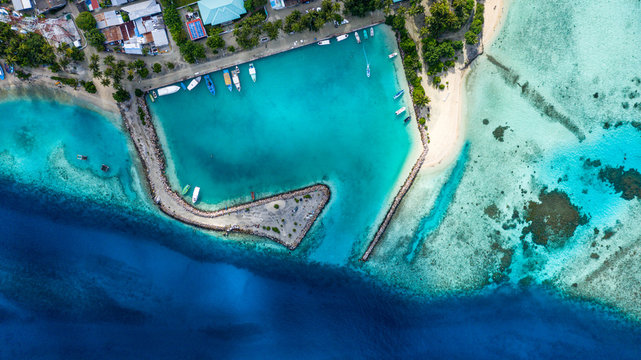 Aerial view of local, inhabited island Felidhoo, located in Vaavu Atoll, Maldives, Indian Ocean with boats / dhonis anchored in the harbour and local beach