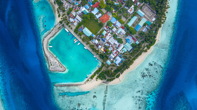 Aerial view of local, inhabited island Felidhoo, located in Vaavu Atoll, Maldives, Indian Ocean with boats / dhonis anchored in the harbour and local beach