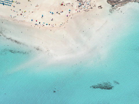 Aerial view of people and parasols by the sea in the amazing La Pelosa beach, Stintino, Sardinia, Italy.