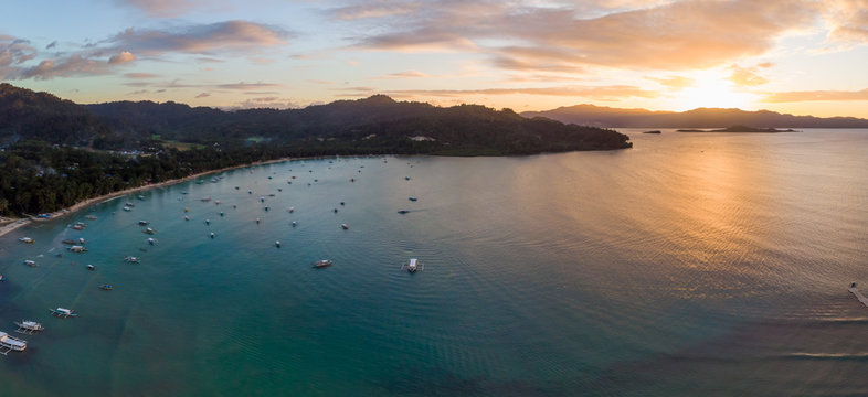 Panoramic aerial view of sunset over the tourist spot Port Barton, showing the beach and outrigger boats in the bay. Port Barton, Palawan, Philippines