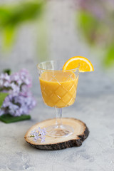 mango and passion fruit smoothie with orange slice as garnish at glass