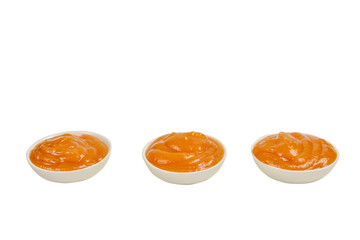 Orange sauce in white plate on white background.