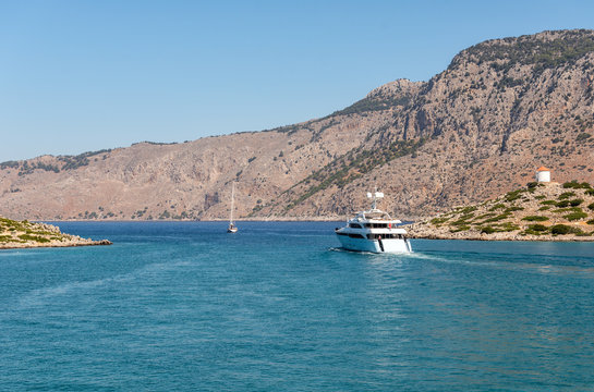 Motor yacht is taking away from blue lagoon at Symi island, Greece