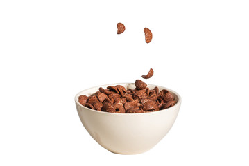 Chocolate corn flakes falling to the white bowl isolated on white. Motion.