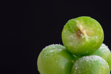 fresh green plum close-up. Plum bitten. black background