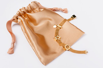 Gold bracelet on golden silk gift bag, jewelry flatlay on neutral background. Top view of fashion...