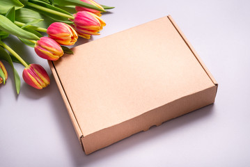 Brown cardboard box and tulip flowers on grey backkground