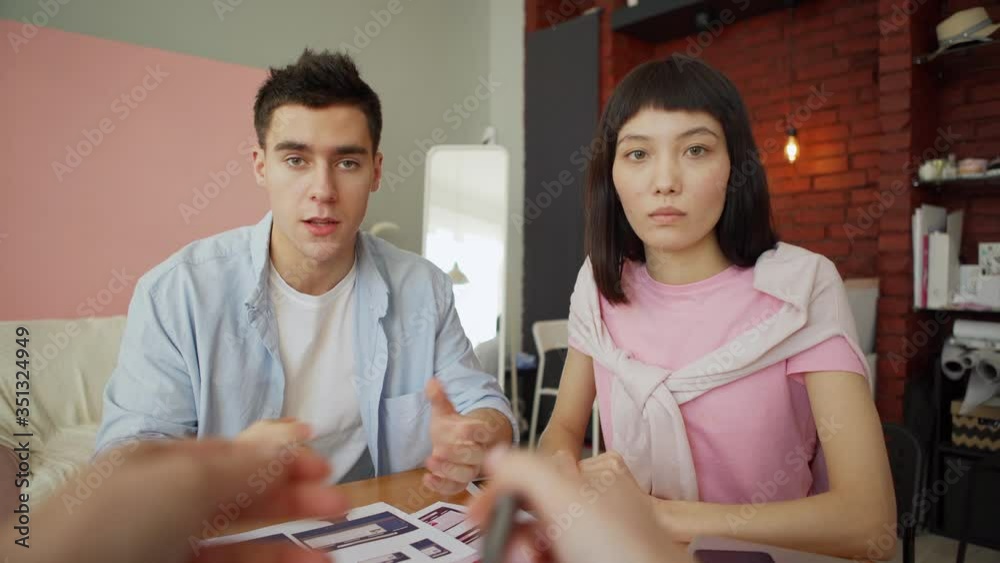 Wall mural pov shot of two diverse young designers presenting printouts with application interface templates fo