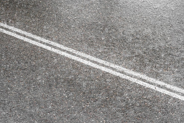 Fototapeta premium Asphalt with two continuous white lines of a road full of water during a rainy day and the drops are splashing the ground