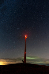 Starry sky with an electric windmill in the middle of a natural landscape