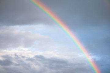 Between the dark rain clouds, clear sky opens and this spectacular rainbow is formed