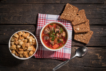 Russian, Ukrainian traditional dish of bright red color from beets, tomatoes, onions and cabbage. a full dinner of soup, crackers and whole grain bread. top view. Tasty and low-calorie soup.