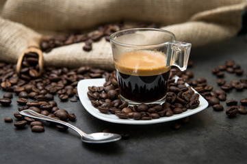 espresso coffee in a glass cup on a black floor with coffee beans cutting light