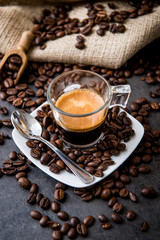 Italian espresso coffee in a glass cup on a black floor with coffee beans cutting light