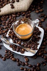 Italian espresso coffee in a glass cup on a black floor with coffee beans cutting light