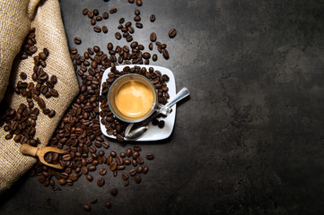 Italian espresso coffee in a glass cup on a black floor with coffee beans cutting light view from top and copy space